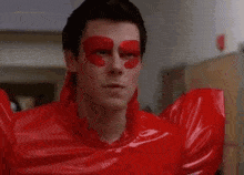 a man is wearing a red latex costume with a red heart on his face .