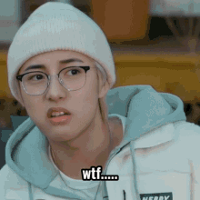 a man wearing glasses and a beanie says wtf on his face