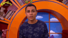 a man is standing in front of a bookshelf with the word ceebies on it