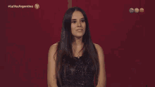 a woman is smiling in front of a red background that says la voz argentina on it