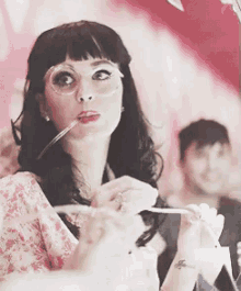 a woman wearing glasses is holding a spoon in her mouth .