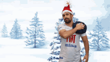 a man wearing a santa hat and a fiat minas shirt stands in front of a christmas tree