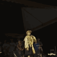 a man is singing into a microphone while wearing a gold jacket
