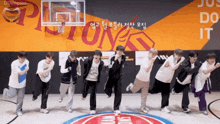 a group of young men are standing on a basketball court in front of a pistons sign
