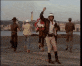 a man in a cowboy hat is carrying a person on his back