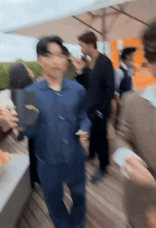 a blurry picture of a man in a blue shirt walking through a crowd of people .