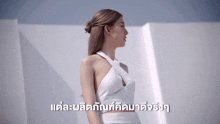 a woman in a white dress is standing in front of a white wall with foreign writing on it