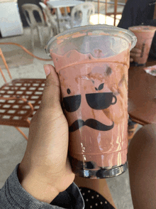 a person is holding a cup with a mustache and a cup on it