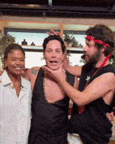 two men and a woman are posing for a picture and one has a red headband on