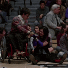 a man in a wheelchair is hugging a woman in a crowd of people