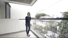 a woman standing on a balcony with a view of a city