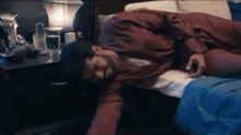 a man is laying on a bed with his head on a nightstand