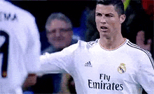 a soccer player wearing a fly emirates jersey is standing in front of another player .