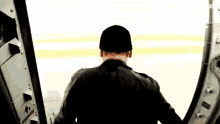 a man in a black jacket and hat is walking down a set of stairs .