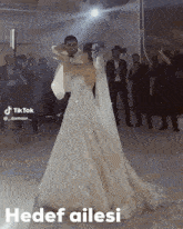 a bride and groom are dancing in front of a crowd with the words hedef ailesi written below them