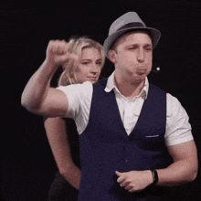 a man wearing a hat and a vest is making a funny face