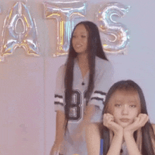 two girls are standing in front of balloons with the letters ats on them