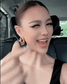 a woman wearing hoop earrings is smiling in a car