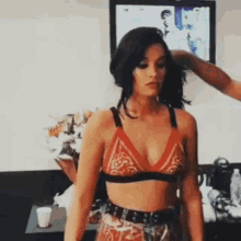a woman in a red bra is getting her hair done by a man in a room .