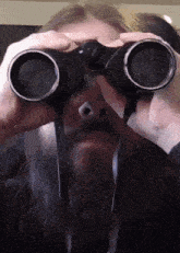 a man with a beard looking through binoculars