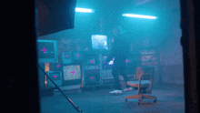 a person standing in a room with a lot of monitors and a chair with a pink cross on it