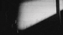 a black and white photo of a person standing in a dark room