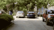 a row of cars are parked in a driveway in front of a house