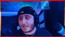 a man wearing headphones and a beanie is sitting in a room .