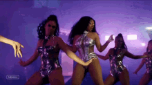 a group of women in metallic outfits are dancing on a stage