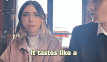 a woman sitting next to a man with the words it tastes like a behind her