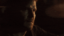 a close up of a man 's face in the dark with a beard .