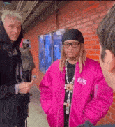a man wearing a pink jacket that says miami is talking to another man
