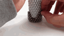 a person is playing with a stack of balls on a table