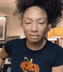 a woman wearing a black shirt with an orange pumpkin on it