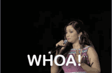 a woman in a pink dress singing into a microphone with the word whoa written below her