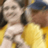 a blurry picture of a man in a yellow shirt and a woman in a yellow shirt .