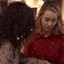 two women are sitting next to each other and one is wearing a red shirt