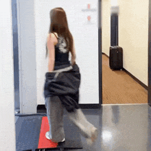 a woman in a black tank top is walking down a hallway