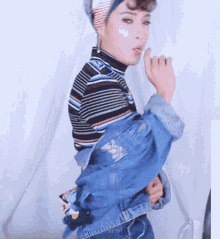 a woman wearing a denim jacket and a striped shirt