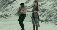 a man and a woman are dancing on a snowy beach .