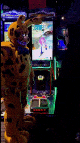 a person in a yellow bunny costume is standing in front of an arcade machine .