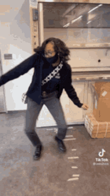 a woman wearing a mask is dancing in a room with boxes on the floor ..