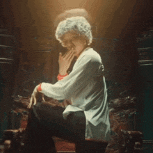 a woman with gray hair is sitting on a chair and making a funny face .