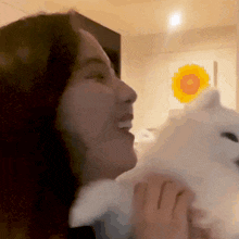 a woman is holding a white dog in her arms