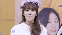 a girl wearing a purple flower crown looks at the camera