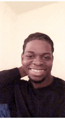 a man with braces on his teeth is smiling for the camera while holding his neck .