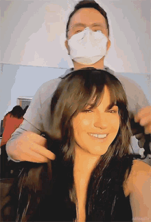 a woman is getting her hair cut by a man wearing a face mask