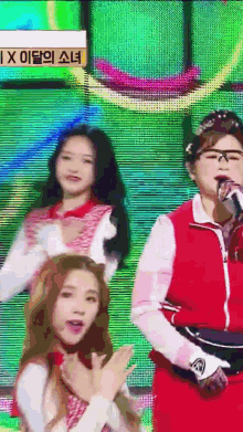 a woman in a red jacket is singing into a microphone in front of a sign that says ix