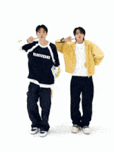 a man in a blue shirt with the word rbu on it is standing next to another man in a yellow jacket