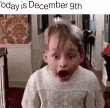 a little boy in a sweater is making a funny face .